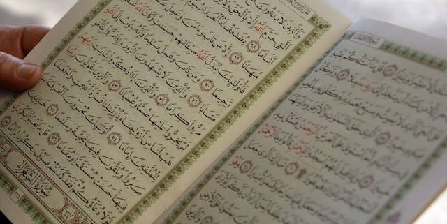 Image: hand holding an open Quran
