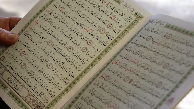 Image: hand holding an open Quran